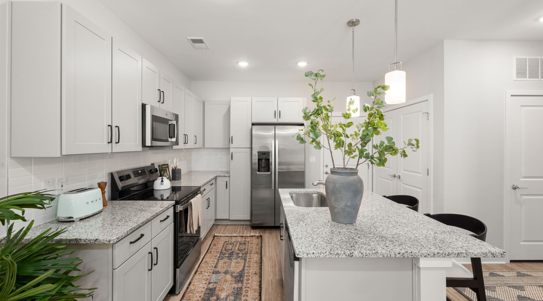 Staged kitchen with an island, stainless steel appliances, and wood like flooring