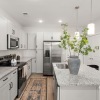 Staged kitchen with an island, stainless steel appliances, and wood like flooring